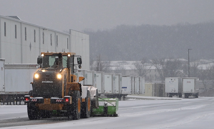 Snow plow at dusk in the loading zone parking lot