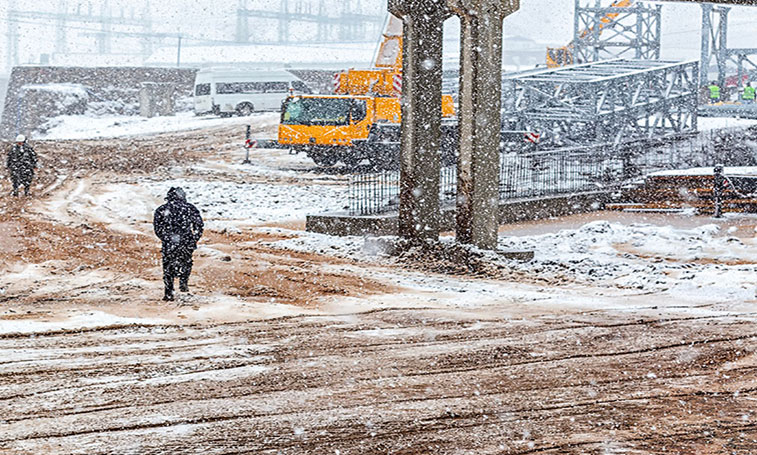 Employee walking through construction site in a snowy blizzard